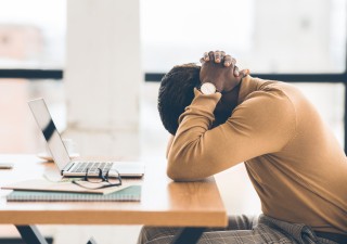 Man, der sein Kopf wegen Burnout haltet