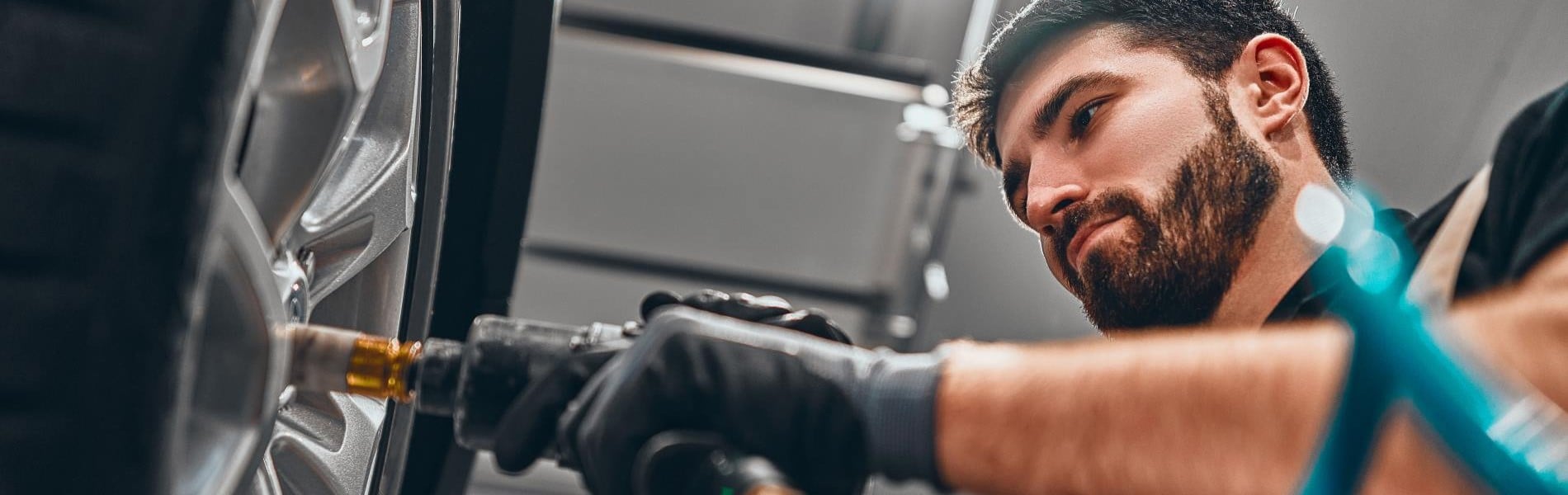 Kfz-Mechaniker schraubt Autoreifen