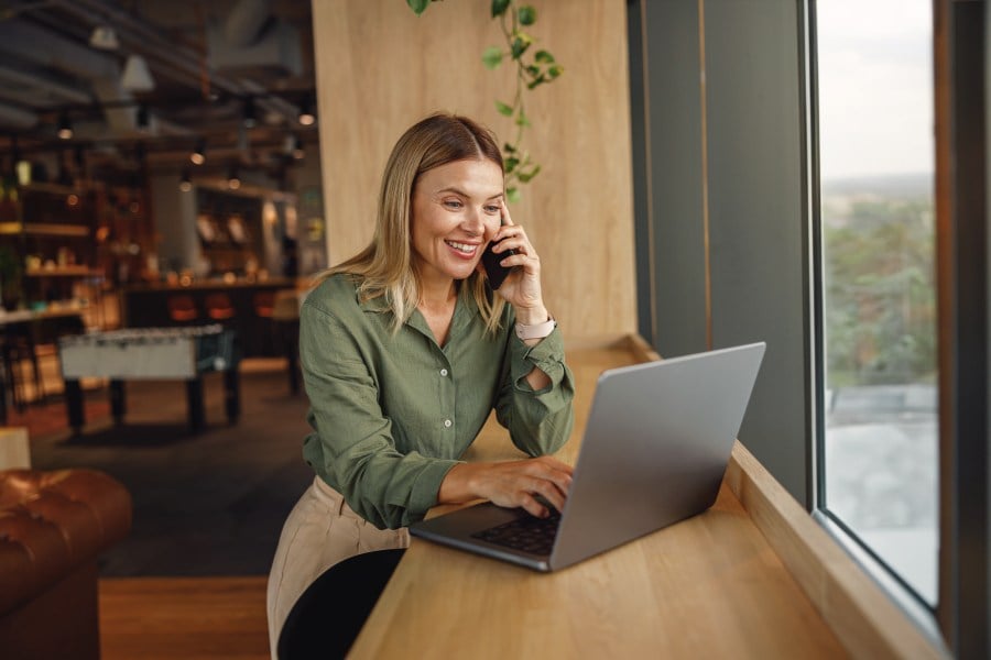 Frau in einem Lokal am Laptop und telefoniert