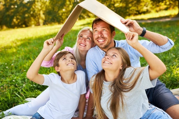 Junge Familie hällt einen Karton als Dach - Kreditversicherung