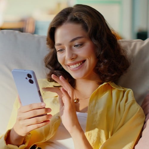 Frau sitzt mit Handy auf dem Couch