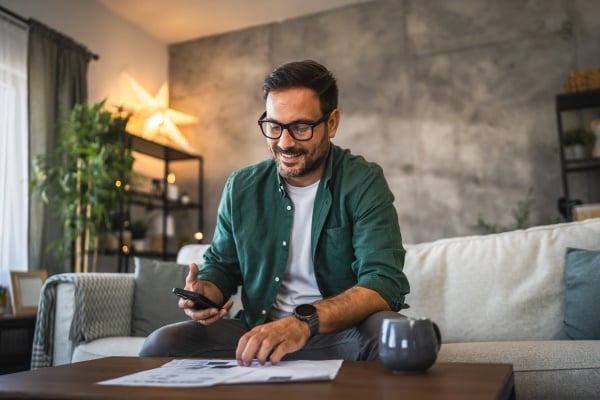 Mann sitzt mit Handy auf der Couch