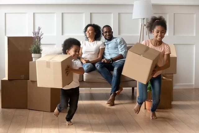 Familie macht Umzug, die Kinder laufen mit den Kartonen in der Hand